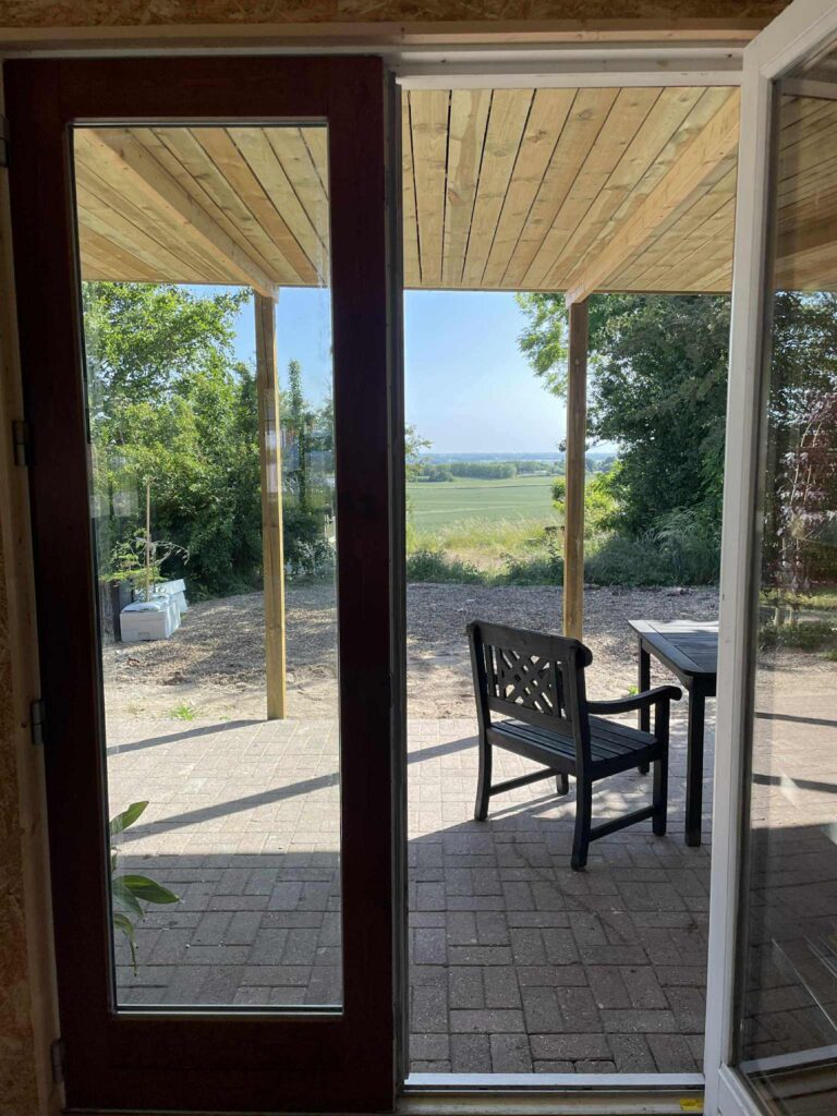 View from the covered terrace with garden furniture, looking out over the fields