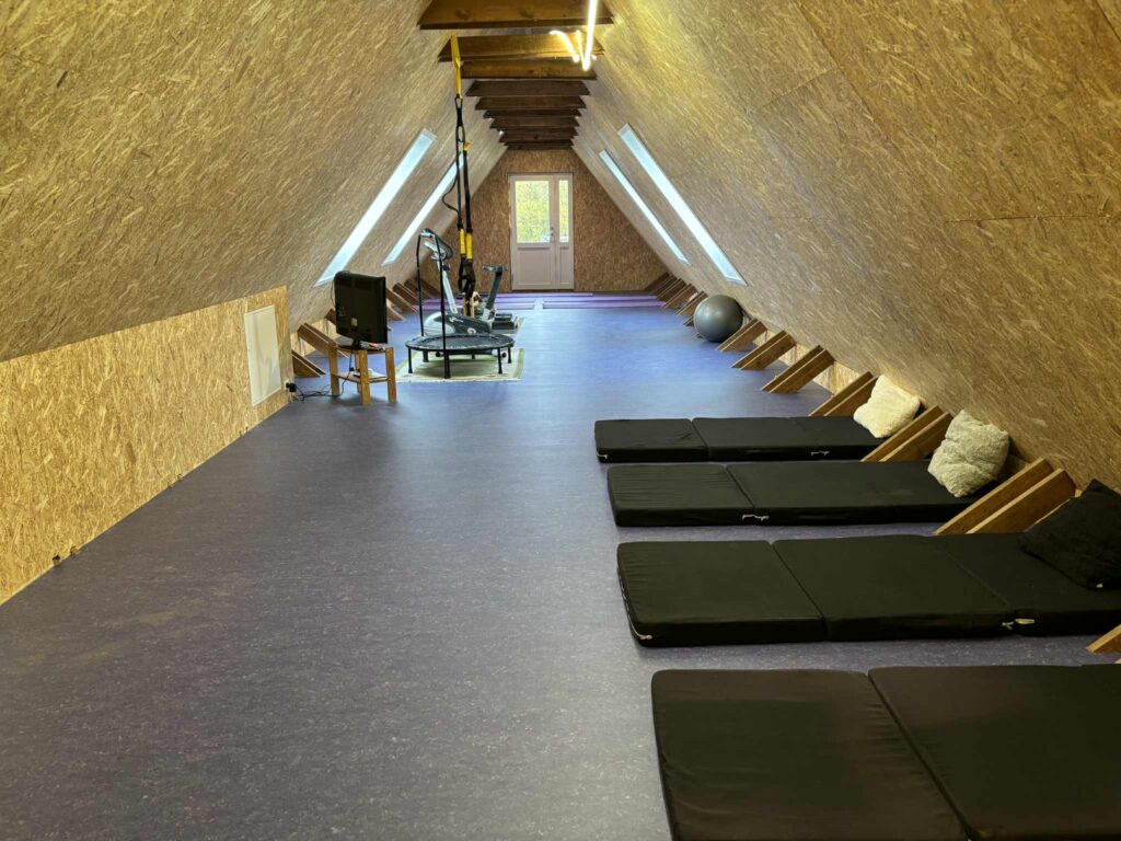 Yoga- og meditationsrum under skråt tag med måtter på gulvet